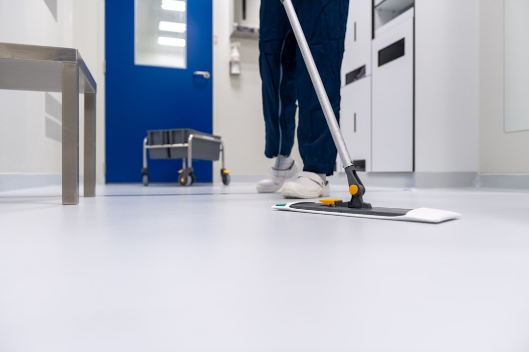 Worker mops a clean white floor in a sterile room.
